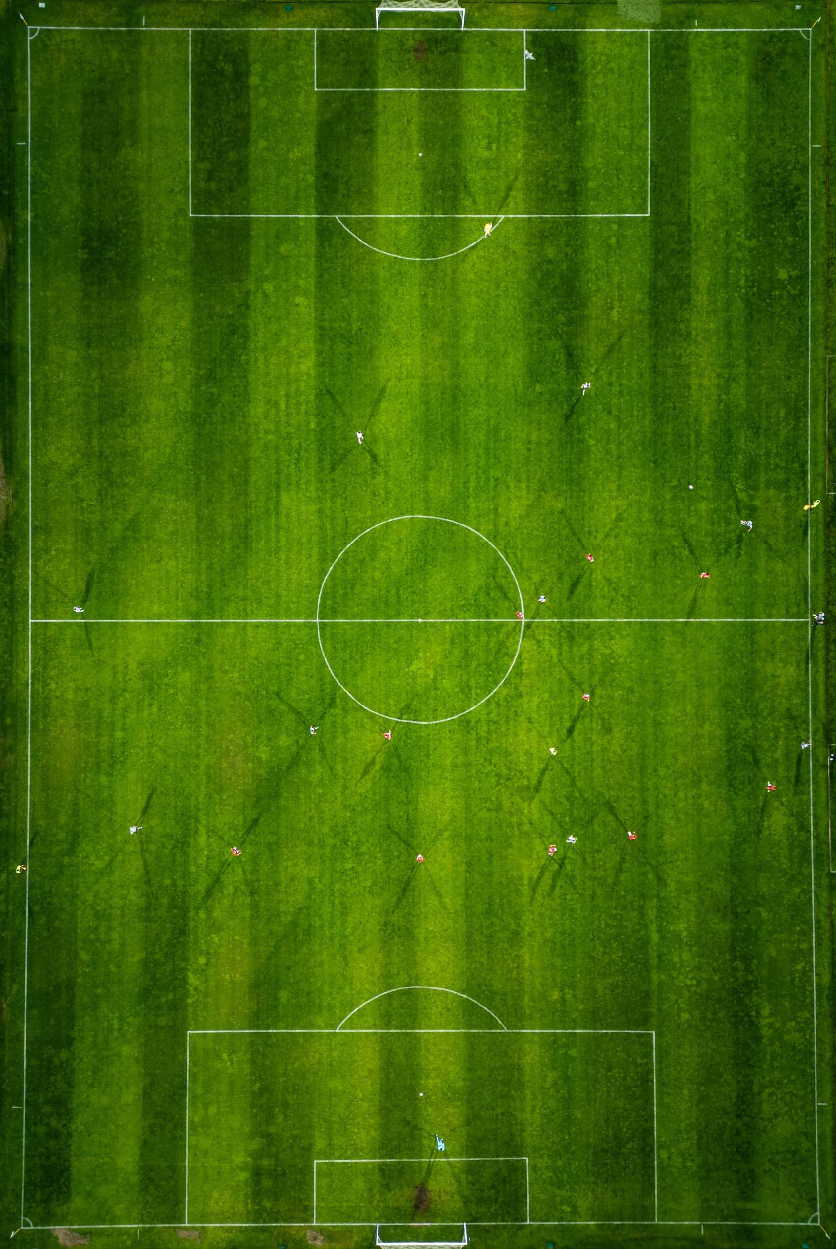Aerial view of a soccer field in action, with players running, passing, and scoring goals