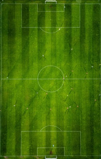 Aerial view of a soccer field in action, with players running, passing, and scoring goals